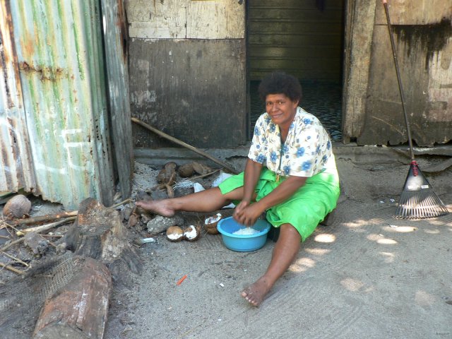 115- Une femme rape des cocos devant sa cuisine 